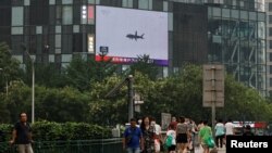 Pedestrians walk past a giant screen broadcasting news report on Chinese People's Liberation Army's (PLA) military exercises around Taiwan, in Beijing, China August 4, 2022.