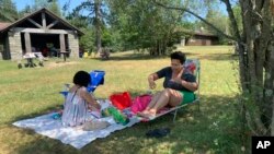 Rosa Chavez, of New York City, applies sunscreen as she and friend Arlene Rodriguez visit Promised Land State Park, July 24, 2022 in Pennsylvania's Pocono Mountains in Greentown, Pa. Residents around the Northeast braced for potentially record-breaking temperatures Sunday as a nearly weeklong hot spell continued.