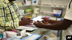 FILE — A man buys a face mask at a pharmacy in Kitwe, Zambia, Feb. 6, 2020. Amid the pandemic, Zambia faced a deadline to clear debt owed to external investors. On Saturday, the IMF announced progress.