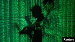 An illustration picture shows a projection of binary code on a man holding a laptop computer, in an office in Warsaw June 24, 2013. (REUTERS/Kacper Pempel)