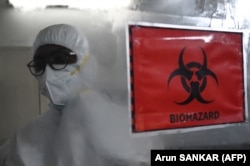 Seorang teknisi yang mengenakan alat pelindung diri (APD) berjalan melewati tanda biohazard di dalam fasilitas laboratorium molekuler yang disiapkan untuk menguji penyakit cacar monyet. (Foto: AFP)