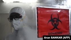 Seorang petugas kesehatan mengenakan alat pelindung diri (APD) berjalan melewati tanda biohazard di dalam fasilitas laboratorium molekuler yang disiapkan untuk menguji penyakit cacar monyet sebagai ilustrasi. (Foto: AFP)