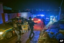 FILE - Police patrol an area in Soweto, South Africa, July 12, 2022 in search of illegal firearms following the weekend shooting in a bar which claimed the lives of 16 people.