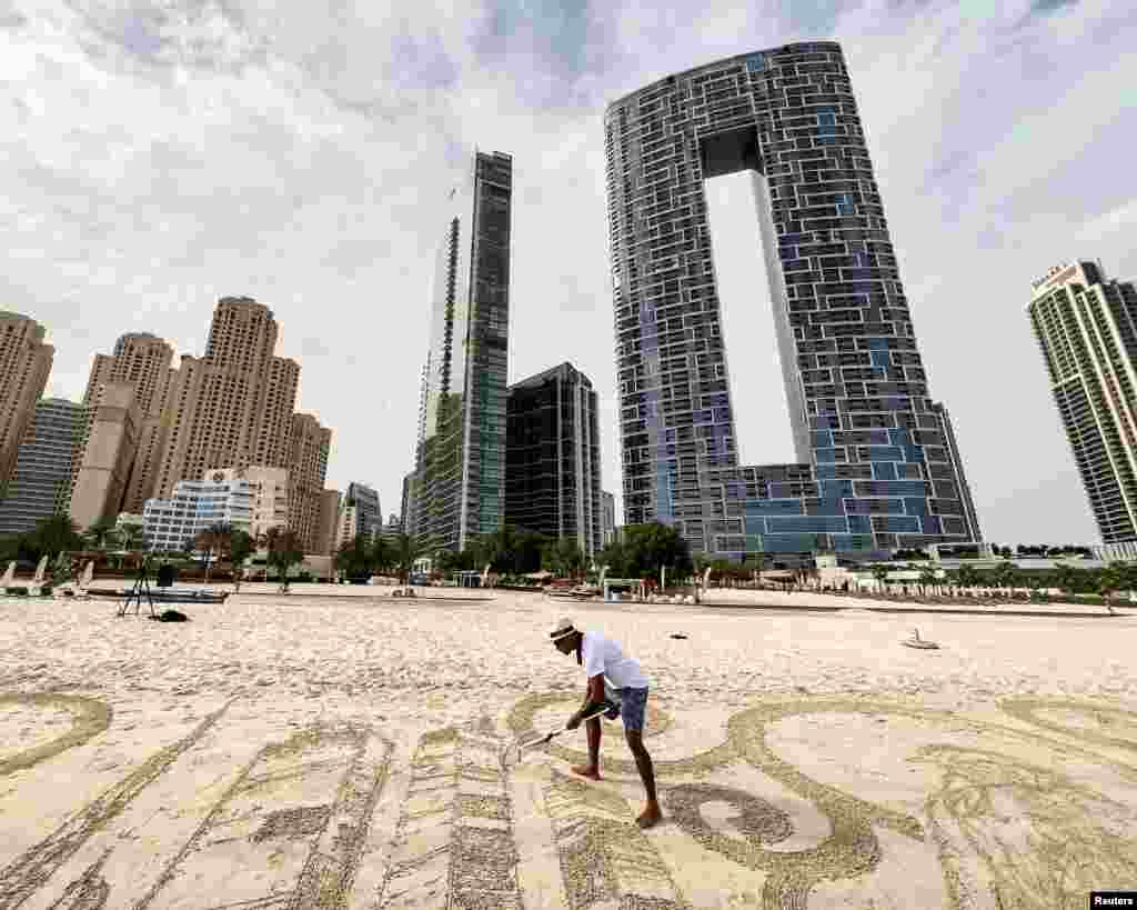 Sand artist Nathaniel Alapide draws on the beach in Dubai, United Arab Emirates.