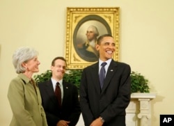 FILE - President Barack Obama smiles as reporters enter the Oval Office of the White House, before the swearing in of Health and Human Services Secretary Kathleen Sebelius, seen left, April 28, 2009, in Washington.
