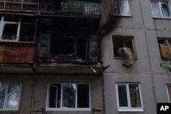 FILE - A woman salvages what she can from her damaged apartment, after a rocket hit her five-story residential building, in Kramatorsk, eastern Ukraine, July 19, 2022.