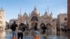 Sejumlah orang tampak berjalan melintasi alun-alun St Mark di Venesia, Italia, yang digenangi oleh banjir rob pada 4 Desember 2021. (Foto: AP/Luigi Costantini)