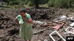 A woman reacts next to a crater caused by Russian bombardments outside her house in the town of Toretske, in Ukraine's Donetsk region, July 17, 2022.