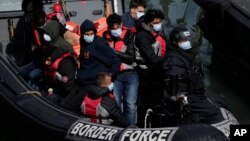 FILE - People thought to be migrants who undertook the crossing from France in small boats and were picked up in the Channel, arrive to be disembarked from a small transfer boat in Dover, south east England, June 17, 2022.
