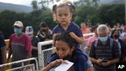 FILE - Alejandra Gomez with her children in tow as they cross the Simon Bolivar International Bridge between San Antonio, Venezuela and Cucuta, Colombia, Aug. 5, 2022.