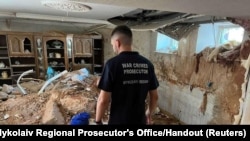 A war crimes prosecutor examines the damage in a destroyed building, as Russia's attack on Ukraine continues, following shelling in Mykolaiv, Ukraine, in this handout picture released on July 31, 2022. 