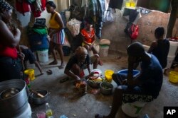 FILE - A woman prepares food at a shelter for families displaced by gang violence in Port-au-Prince, Haiti, Dec. 9, 2021.