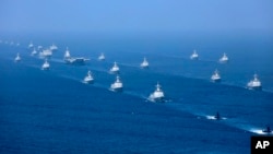 In this April 12, 2018 photo released by Xinhua News Agency, the Liaoning aircraft carrier is accompanied by navy frigates and submarines conducting an exercises in the South China Sea.