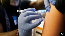 FILE - A person gets a Pfizer COVID-19 vaccine booster shot, Dec. 20, 2021. COVAX, the global program for distributing COVID-19 vaccines to poorer countries, will soon be integrated into more routine vaccination programs.