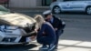 FILE - A Kosovo police officer helps a Serb driver place stickers covering state symbols on her car's license plates, at Merdare border crossing, Oct. 4, 2021.