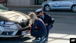 FILE - A Kosovo police officer helps a Serb driver place stickers covering state symbols on her car's license plates, at Merdare border crossing, Oct. 4, 2021.