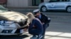 FILE - A Kosovo police officer helps a Serb driver place stickers covering state symbols on her car's license plates, at Merdare border crossing, Oct. 4, 2021.