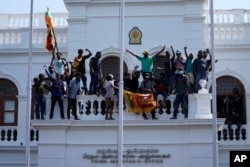 Sri Lankan protesters stand on top of prime minister Ranil Wickremesinghe 's office, demanding he resign after president Gotabaya Rajapaksa fled the country amid economic crisis in Colombo, July 13, 2022.