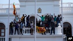 Sri Lankan protesters stand on top of prime minister Ranil Wickremesinghe 's office, demanding he resign after president Gotabaya Rajapaksa fled the country amid economic crisis in Colombo, July 13, 2022.