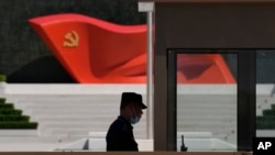 FILE: A security guard stands near a sculpture of the Chinese Communist Party flag at the Museum of the Communist Party of China on May 26, 2022, in Beijing. China said it was conducting military exercises July 30 off its coast.