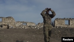 Армянский солдат смотрит в бинокль, стоя на боевых позициях возле села Тагавард в районе Нагорного Карабаха, 11 января 2021 года (REUTERS)
