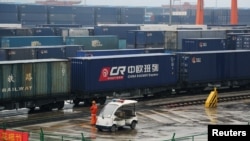 ພະນັກງານຄົນນຶ່ງຢືນຢູ່ໃກ້ລົດໄຟ ທີ່ບັນທຸກຕູ້ສິນຄ້າທັງຫຼາຍ ຂອງ China Railway Express ຢູ່ທີ່ ສະຖານີລາງລົດໄຟທ່າເຮືອ Chongqing, ວັນທີ 30 ມີນາ 2019.