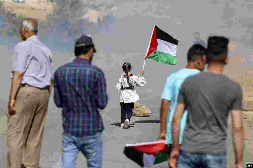A girl carries the Palestinian flag during demonstrations against Israeli settler attacks near al-Mughayer village, east of Ramallah in the occupied West Bank.
