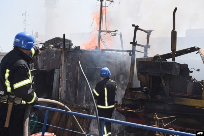 A handout image made available by the Odesa City Council Telegram channel, July 24, 2022, shows Ukrainian firefighters battling a fire on a boat burning in the port of Odesa after missiles hit the port, July 23, 2022.
