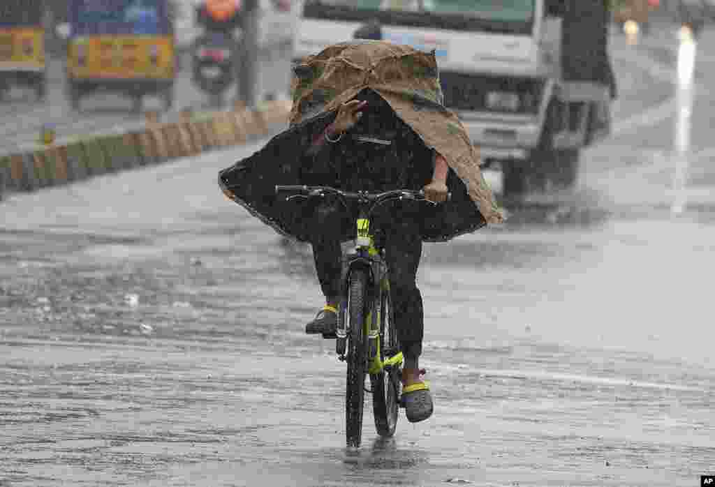 A man rides a cycle in the rain in Hyderabad, India.