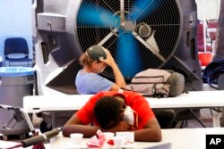 People try to keep cool at the Justa Center, a resource center catering to the older homeless population, as temperatures hit 110-degrees, in Phoenix, July 19, 2022.