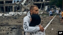 Una pareja reacciona después del bombardeo ruso en Mykolaiv, Ucrania, el 3 de agosto de 2022. El supermercado, los edificios de gran altura y la farmacia resultaron dañados, según los medios locales.
