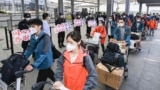 FILE - In this photo released by China's Xinhua News Agency, members of a COVID-19 testing team are greeted at an airport in Shanghai, China, as they prepare to return home to Hubei Province, May 14, 2022.