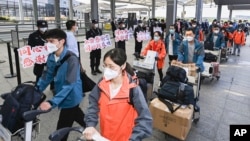 FILE - In this photo released by China's Xinhua News Agency, members of a COVID-19 testing team are greeted at an airport in Shanghai, China, as they prepare to return home to Hubei Province, May 14, 2022.