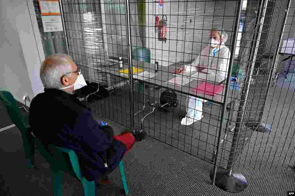 A doctor, left, is seen at the welcome desk of a consultation center dedicated to COVID-19 suspected patients in Tinteniac, western France.