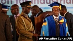 Zimbabwe's President Robert Mugabe, center-right, arrives to preside over a student graduation ceremony at Zimbabwe Open University on the outskirts of Harare, Zimbabwe Friday, Nov. 17, 2017. Mugabe is making his first public appearance since the military put him under house arrest earlier this week. (AP Photo/Ben Curtis)