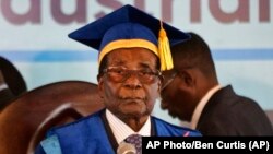 Zimbabwe's President Robert Mugabe, center-right, arrives to preside over a student graduation ceremony at Zimbabwe Open University on the outskirts of Harare, Zimbabwe Friday, Nov. 17, 2017. Mugabe is making his first public appearance since the military put him under house arrest earlier this week. (AP Photo/Ben Curtis)