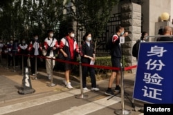 北京考生在进入高考考场前排队等候测量体温。（2022年6月7日）