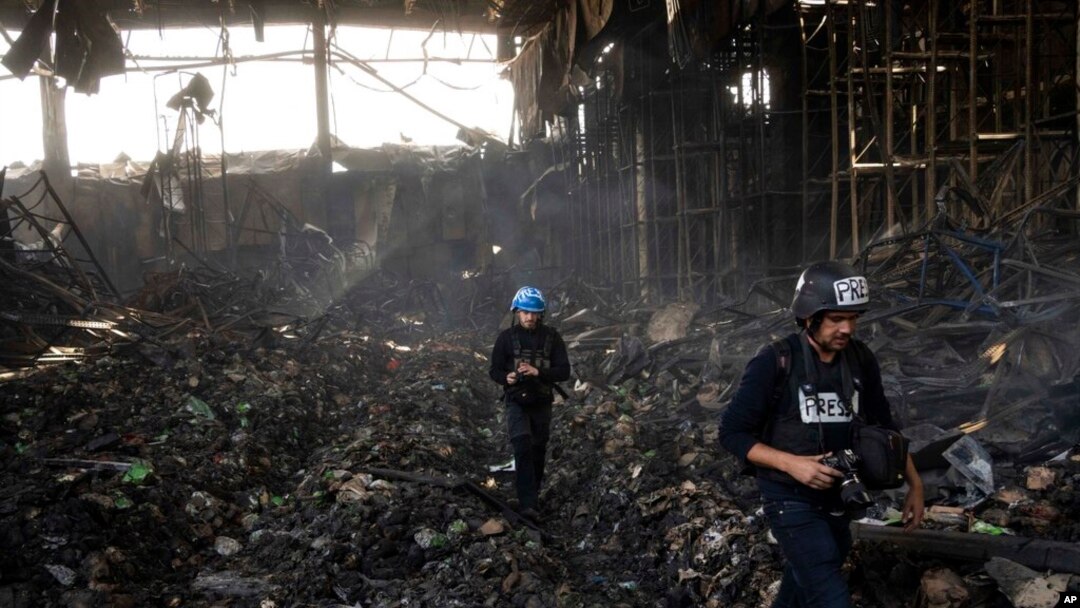 Wartawan berjalan di dalam gudang yang hancur untuk menyimpan makanan, setelah serangan dari Rusia di Brovary, di pinggiran Kyiv, Ukraina, 29 Maret 2022. (Foto: AP)