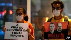 National Indigenous Foundation (FUNAI) employees hold posters with images of British journalist Dom Phillips, left, and Indigenous official Bruno Araujo Pereira during a vigil in Brasilia, Brazil, June 9, 2022. The sign at left reads "FUNAI Employees' Lives Matter" in Portuguese.