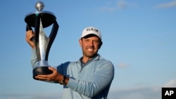 Charl Schwartzel of South Africa holds up the trophy for winning the inaugural LIV Golf Invitational at the Centurion Club in St. Albans, England, June 11, 2022.