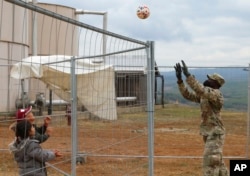 FILE - In this image provided by the U.S. Army, Army Pfc. Rafiou Affoh, a carpentry and masonry specialist, plays a game of volleyball with Afghan evacuees at Camp Liya, Kosovo, Oct. 1, 2021.