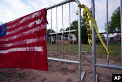 FILE - A barricade blocks access to Robb Elementary School, where a memorial has been created to honor the victims killed in the recent school shooting, in Uvalde, Texas, June 3, 2022.