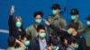 FILE - Pro-democracy activist Leung Kwok-hung, also known as 'Long Hair,' gestures as he walks to a prison van with other activists to head to court over a national security law charge, in Hong Kong, March 4, 2021.