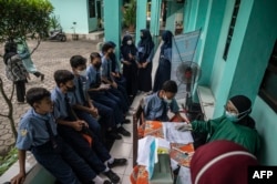 Petugas kesehatan melakukan tes antigen COVID-19 pada siswa SMP di Surabaya, pada 9 Juni 2022. (Foto: AFP/Juni Kriswanto)