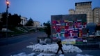 Un hombre camina junto a sacos de arena que forman la palabra "Ayuda" en la plaza Maidan en Kyiv, Ucrania, el 6 de junio de 2022. (Foto AP/Natacha Pisarenko)