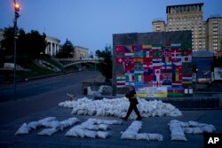 A man walks by sand bags forming the word "Help" at Maidan square in Kyiv, Ukraine, June 6, 2022.