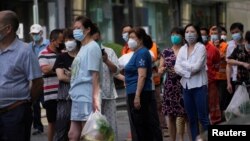 Người dân xếp hàng chờ xét nghiệm trên một con phố, trong bối cảnh các biện pháp ngăn chặn mới được áp đặt ở một số khu vực của thành phố nhằm hạn chế sự bùng phát COVID-19 ở Thượng Hải, Trung Quốc, ngày 11 tháng 6 năm 2022.
