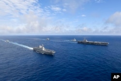 Kapal induk bertenaga nuklir AS USS Ronald Reagan, kanan, dan kapal helikopter platform pendaratan (LPH) Korea Selatan (LPH) Marado, kedua dari kiri, berlayar selama latihan militer bersama di lokasi yang dirahasiakan, Sabtu, 4 Juni 2022. (Foto: via AP)