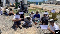 This image provided by Muhammad Arif Sarwari, shows Afghans who fled the Taliban takeover of their country staging a protest at Camp Bondsteel in Kosovo, June 1, 2022.