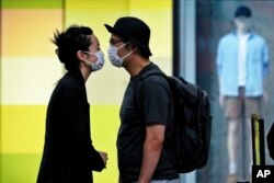 A couple wearing face masks move in closer to kiss as they line up for their COVID-19 tests at a testing facility near a shopping mall where most shops have ordered to closed as part of COVID-19 controls in Beijing, June 13, 2022.